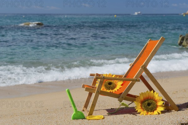 Empty beach chair with flowers and toys at the sea
