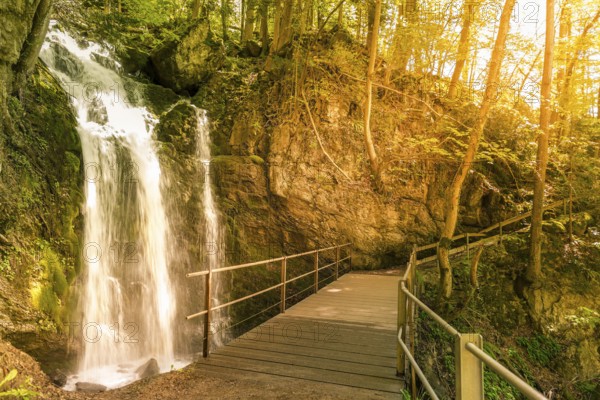 Idyllic scenery of a small waterfall and a bridge that crosses it, in the forests of the Swiss Alps from Walensee, St Gallen Canton, Switzerland, Europe