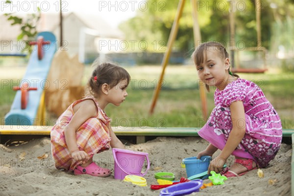 Two girls play in the sandbox at the playground