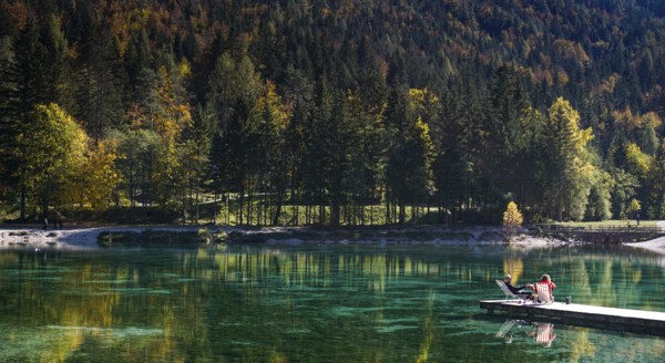 Kranjska Gora, Slovenia, 18 October, 2021: tourists enjoy relaxing on the wooden dock at Lake Jasna in the Slovenian Alps, Europe