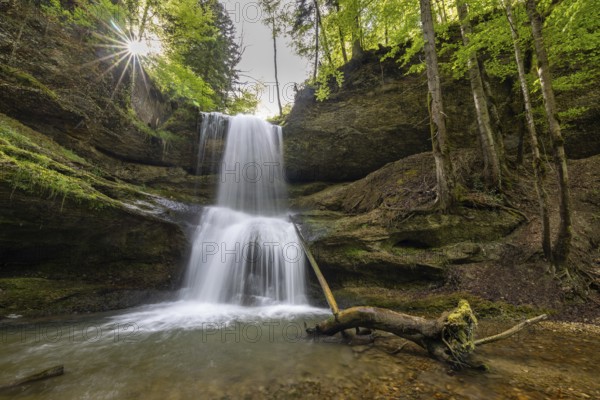 Waterfall with in the forest, where the sun rays penetrate through the trees, forming a peaceful scenery, Hasenreuter Wasserfall, Scheidegg, Bavaria, Germany, Europe