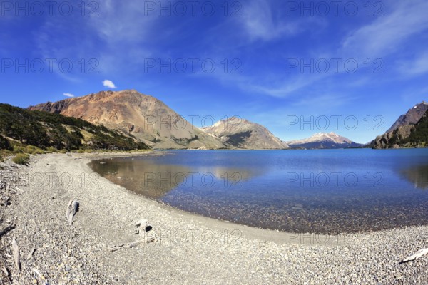 Oval blue lake surrounded by mountains. Mountains reflected in the mirrored water. Picture taken Fisheye lens