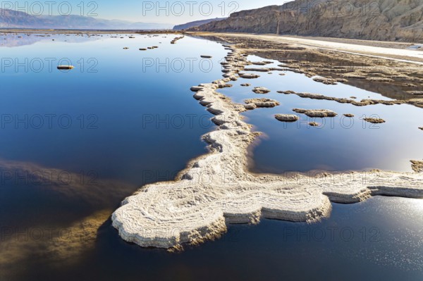 Evaporated salt patterns on the surface of the blue water. The photo was taken from a drone. Magic of the Dead Sea. Cold sunny winter day. Israel