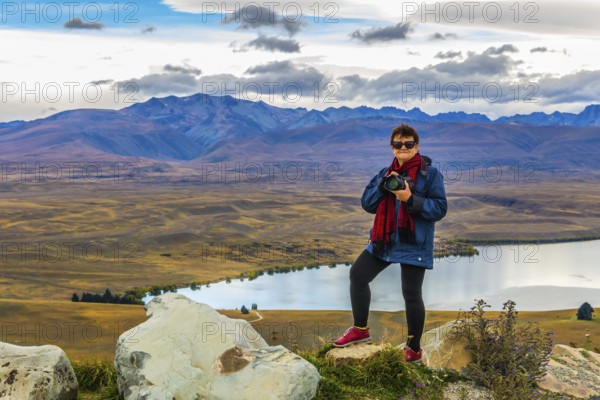 Woman photographer on the mountain. Exotic journey to the South Island, New Zealand. Concept of active and ecological tourism