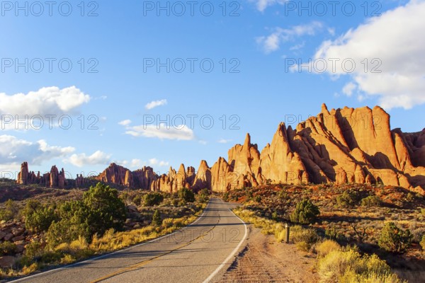 Asphalt road in the park. Arches Park in Utah, USA. Picturesque red-brown sandstone cliffs form a unique landscape. The unique beauty of Arches Park. Grandiose rock compositions natural origin