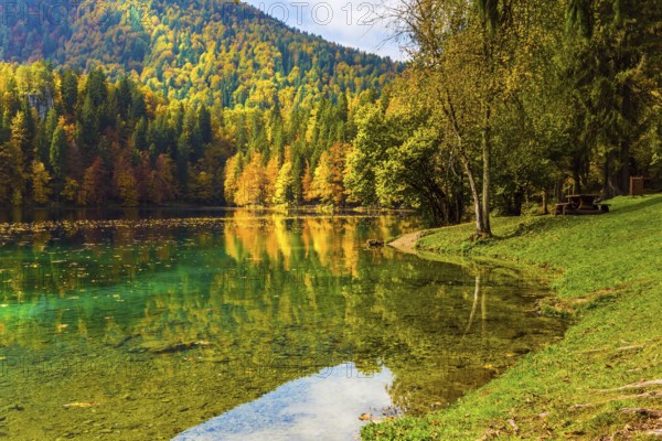 Flood after rain. The quiet lake in Northern Italy, Lago de Fusine. Concept of cultural and ecological tourism. Scenic reflections of multicolored forests in the smooth water of the lake