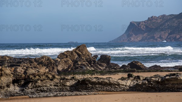 Rocky coast with large stones, behind it the sea with gentle waves under a clear blue sky, Praia de Arriba, Portugal, Europe