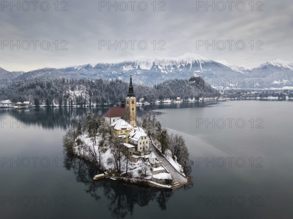 Aerial shot of lake Bled on a calm winter morning with snow