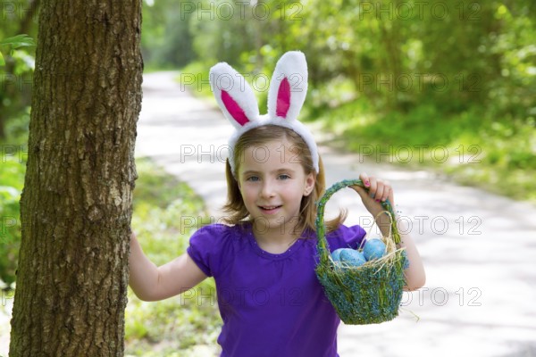 Easter girl with eggs basket and funny bunny ears on the forest