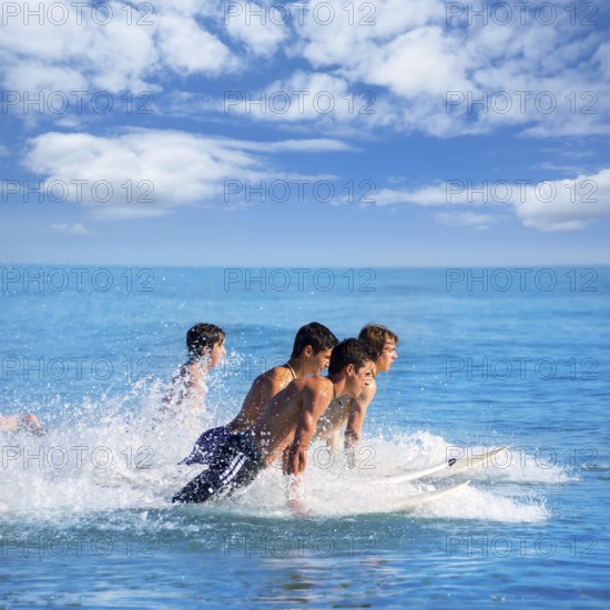 Boys teen surfers surfing running jumping on surfboards at the beach