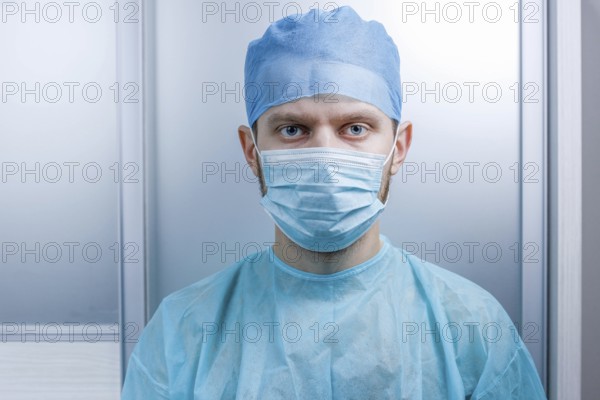Doctor facing the camera, dressed in mask and scrubs in a clinical setting