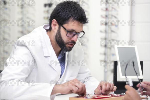 Ophthalmologist showing a tray with different glasses to a customer