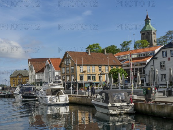 A harbour with several boats in front of colourful buildings under a blue sky with few clouds, Stavanger, Norway, Europe