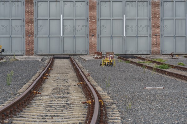 Empty rails lead to large grey doors on gravel, bochum, westphalia, germany