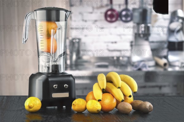 Metal food blender close-up with fresh exotic tropic fruits next to it on kitchen background with empty space. Blender and wooden table in kitchen