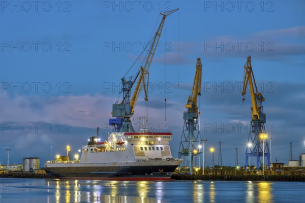 Three yellow and blue cranes at dusk in the harbour of Belfast, Northern Ireland