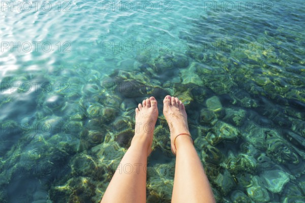 Ibiza girl legs at Portinatx beach pier clear water in Balearic Islands