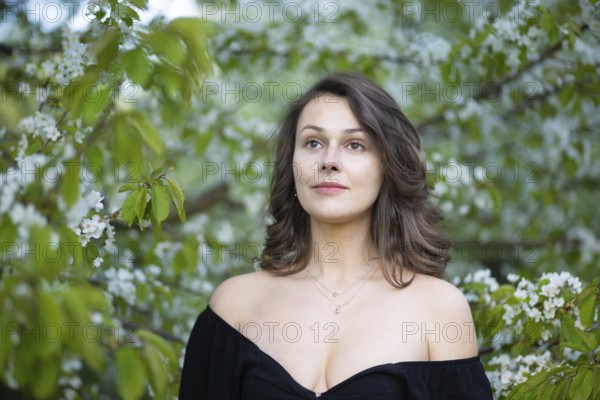 Close-up of a woman surrounded by green leaves and white blossoms