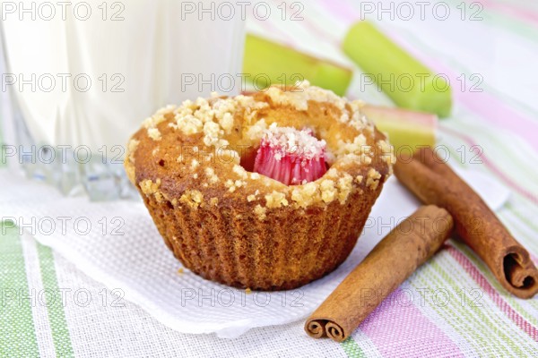 Cupcake with rhubarb, cinnamon on a white paper napkin, rhubarb, milk in a glass on a background of a linen tablecloth