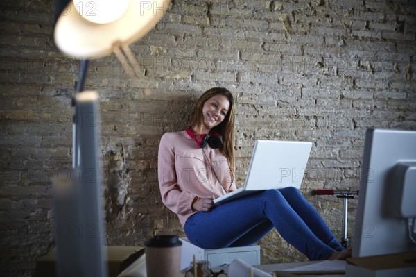 Businesswoman young casual sitting at office working with laptop computer feet on table relaxed