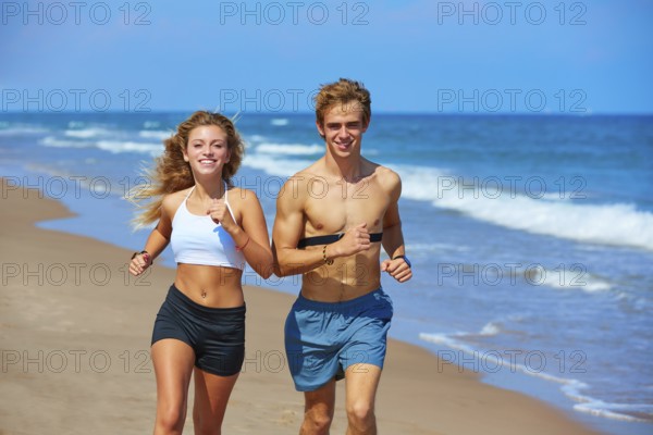 Blond young couple running on the beach in summer vacation