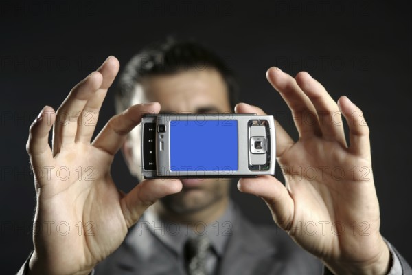 Businessman taking photos, mobile camera, black background