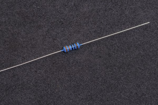 A blue-striped resistor with long leads on a dark background