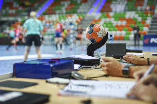 Ball on the referee's table and handball match in the background