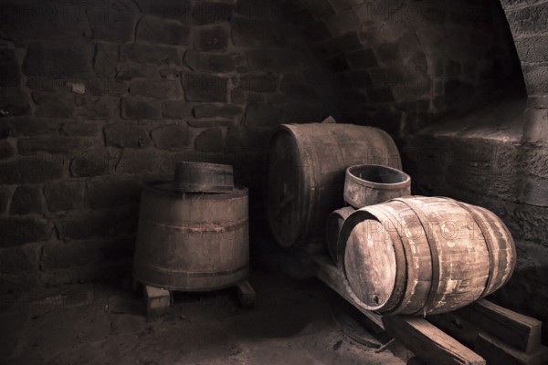 Vintage image with the interior of a stone wine cellar and aged wooden barrels, in low light. Perfect background or frame for a country life concept or medieval way of making wine