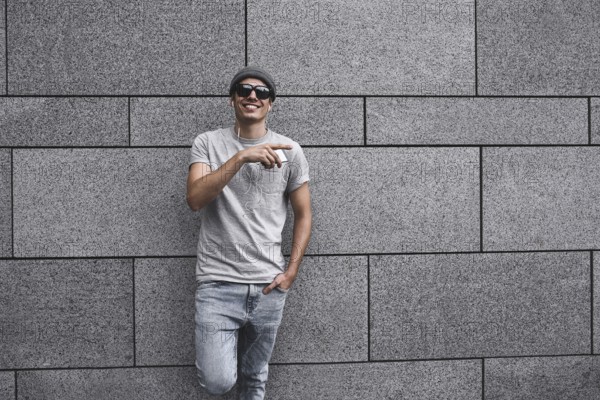 People, technology, travel and tourism, man with earphones, smartphone on city street and listening to music over gray wall background