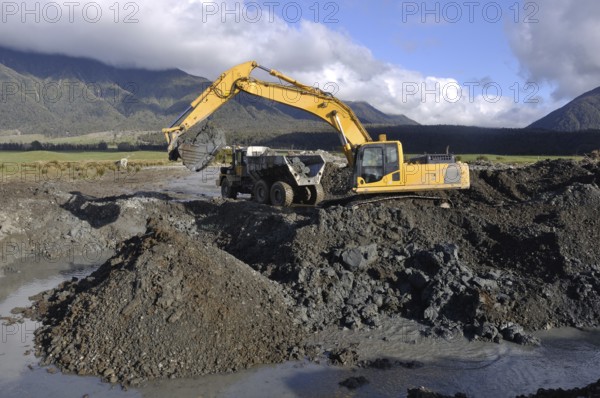 30 ton digger collects blue clay for lining an effluent pond next to a rotary dairy in Westland, New Zealand, Oceania