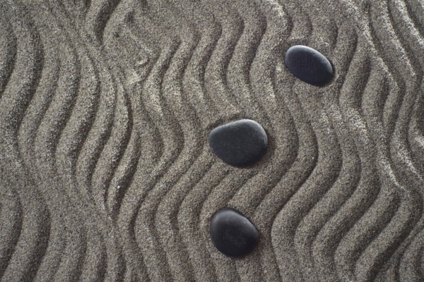 Drawings on light gray sand and black stones in a small Zen garden