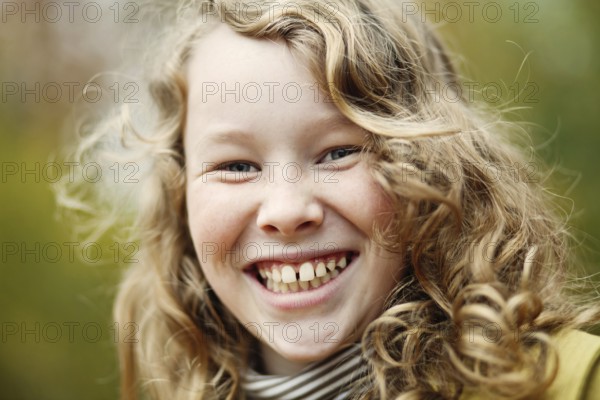 Outdoor portrait of smiling blond girl in autumn park, Belgium, Europe