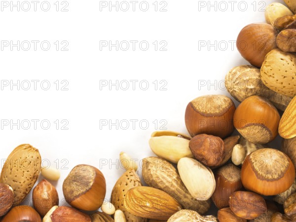 Background of closeup mixed nuts - hazelnuts, almonds, walnuts, pistachios, peanuts, pine nuts peeled and not peeled - with copy space. Isolated one edge. Top view or flat lay