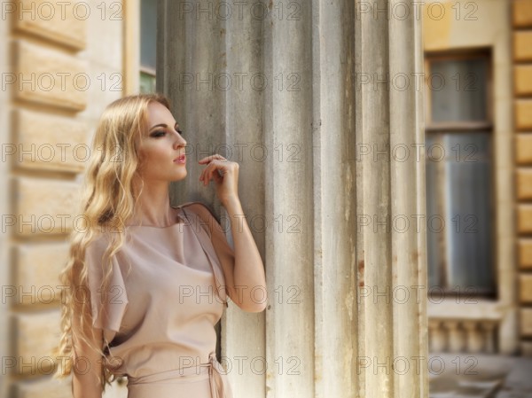 Beautiful blond woman in beige long dress outdoors