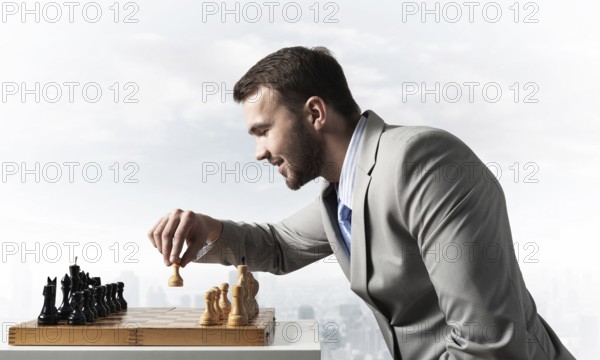 Concentrated businessman playing chess game. Successful management and leadership concept. Confident young man in business suit sitting at desk with chess. Operative tactics and strategy planning