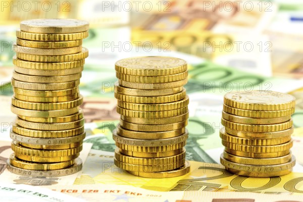Stack of coins, falling curve, symbolic photo for falling interest rates and falling costs Austria