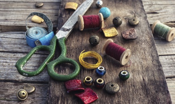 Outdated tools and jewellery for needlework on wooden background
