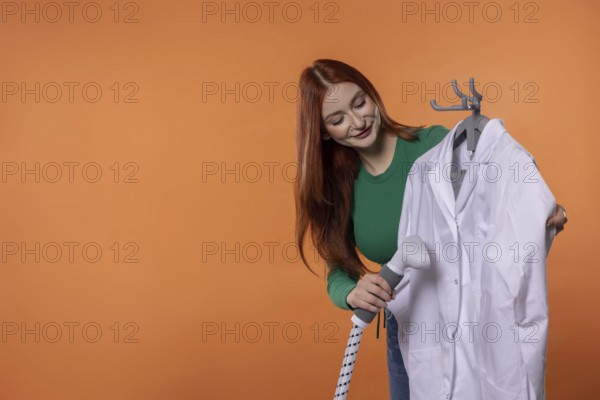 A young woman smiles while preparing a clean white lab coat, showing her care for professional attire and detail