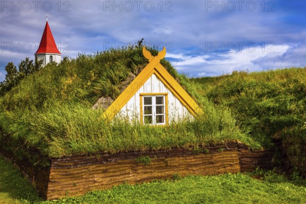 The village of houses covered with turf and grass. Church bell tower with red gabled roof. Ethnographic Museum-estate Glaumbaer, Iceland. The concept of the historical and cultural tourism