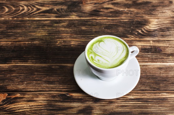 Top view of the cup Matcha latte on wooden background. The concept of green tea as an art
