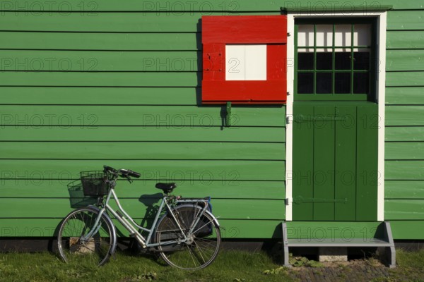 Bicycle parked in front of a green painted timbered house on the Dutch tourist attraction Zaanse Schans