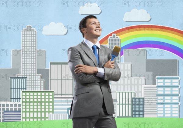 Confident and creative businessman painter standing with arms folded. Happy handsome man in business suit and tie holding paintbrush on city background. Cityscape illustration with colorful rainbow