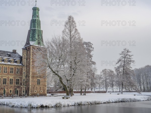 Snow-covered castle and lake in winter with trees and historic architecture, Raesfeld, münsterland, germany