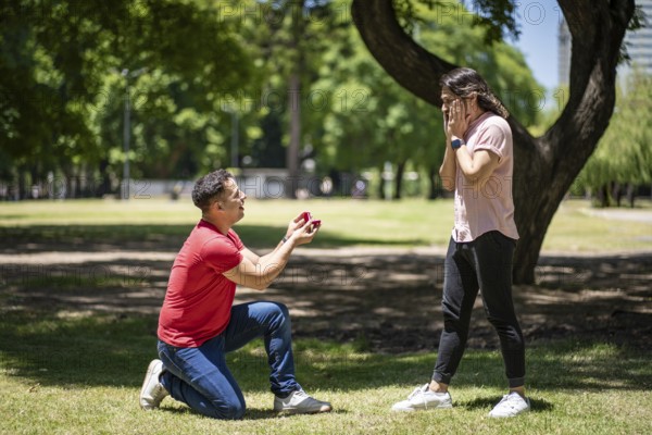 Young man surprising his boyfriend in a park with a wedding ring