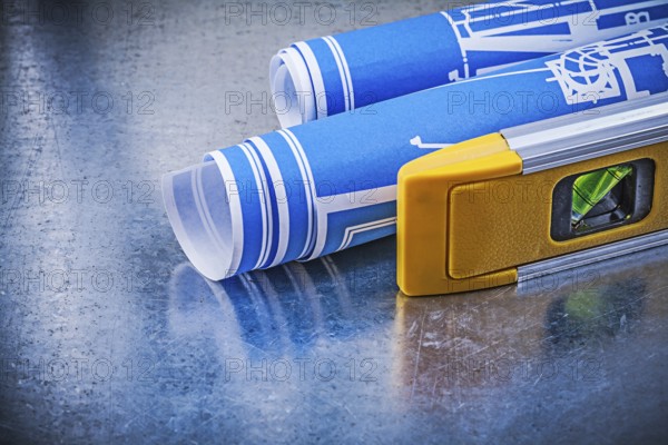 Rolled up blueprints construction level on metallic background