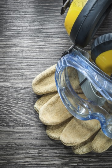 Safety gloves goggles earmuffs on wooden board
