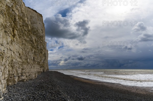Landscape view of a black rock beach on the Jurassic Coast of England with tall chalkstone cliffs