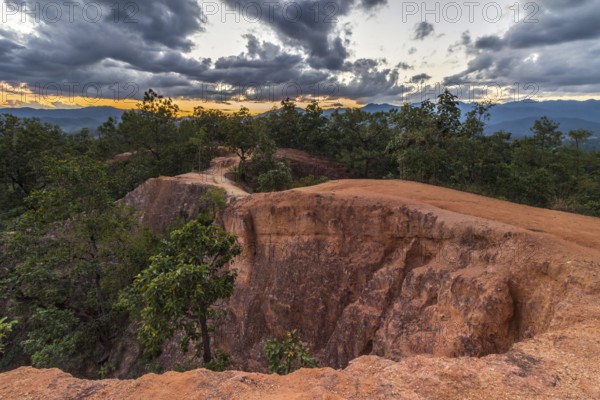 Canyon near Pai city cloudy sky at sunset. Red sandy path and rocky walls. Mae Hong Son province, northern Thailand