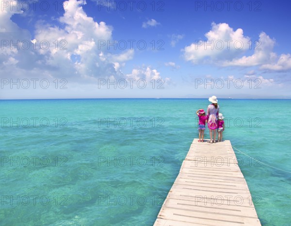 Daughters and mother in jetty on Formentera with turquoise sea